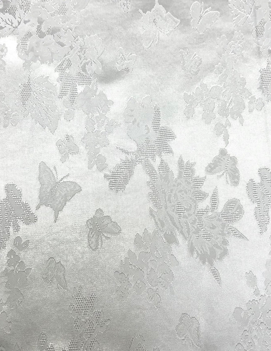 Close-up of pale gray woven fabric with a scattered floral and butterfly motif in slightly darker gray.