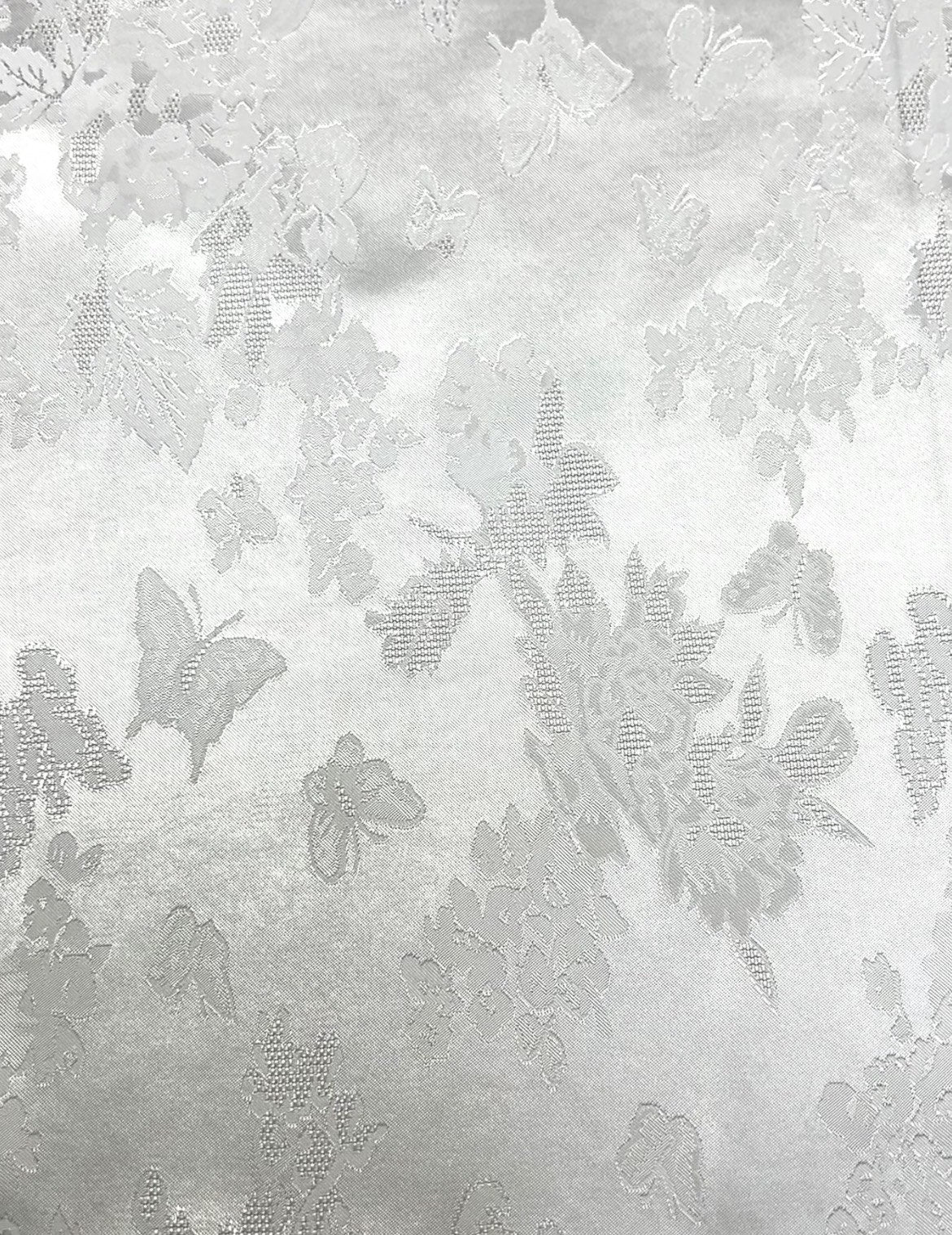 Close-up of pale gray woven fabric with a scattered floral and butterfly motif in slightly darker gray.