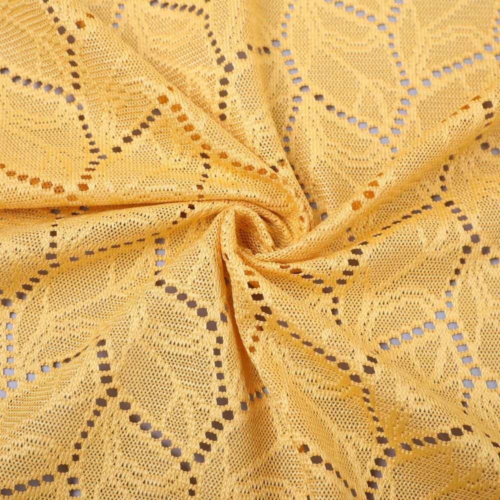 Close-up of golden yellow openwork lace fabric, spread in a repeating geometric pattern and gathered into a twist at the center.