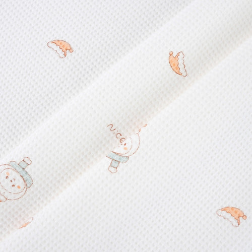 Close-up of white textured fabric with sparse peach and pale blue cartoon motifs.