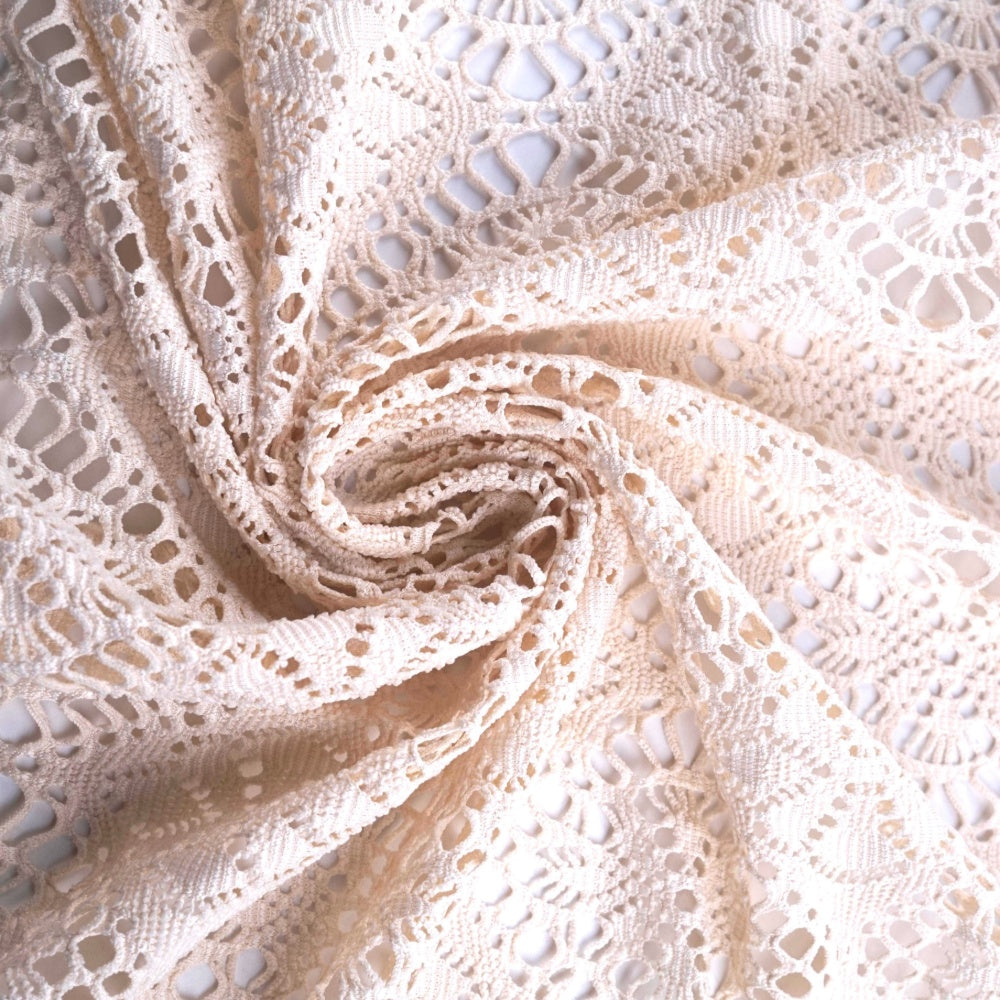 Ivory lace fabric with intricate openwork floral and geometric motifs, loosely gathered into a spiral of folds.