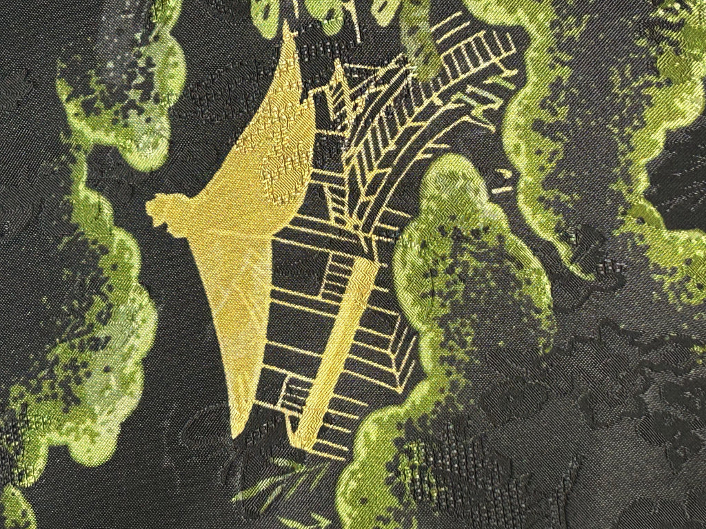 Close-up of dark charcoal fabric with a woven motif of yellow-green foliage and a gold Eiffel Tower design.
