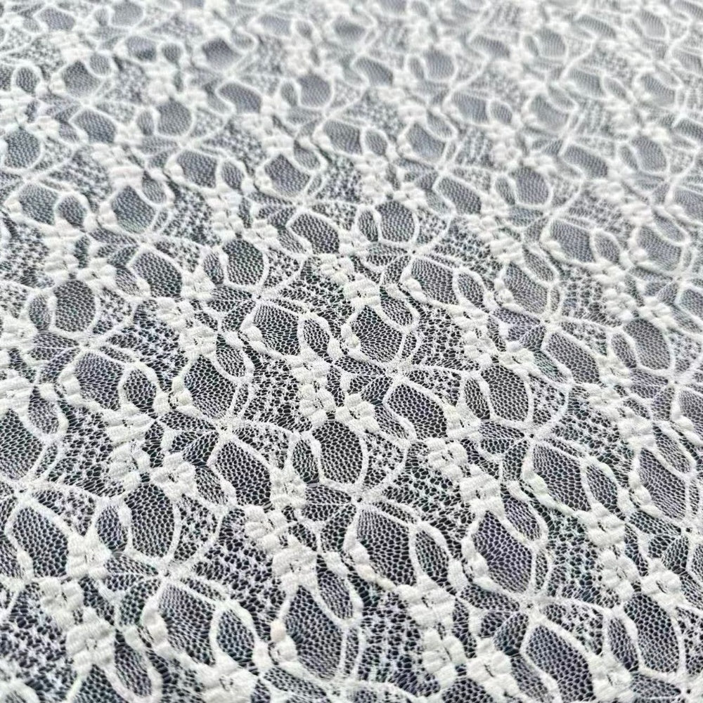 Close-up of white floral lace with repeating oval mesh openings and small embroidered flower clusters.