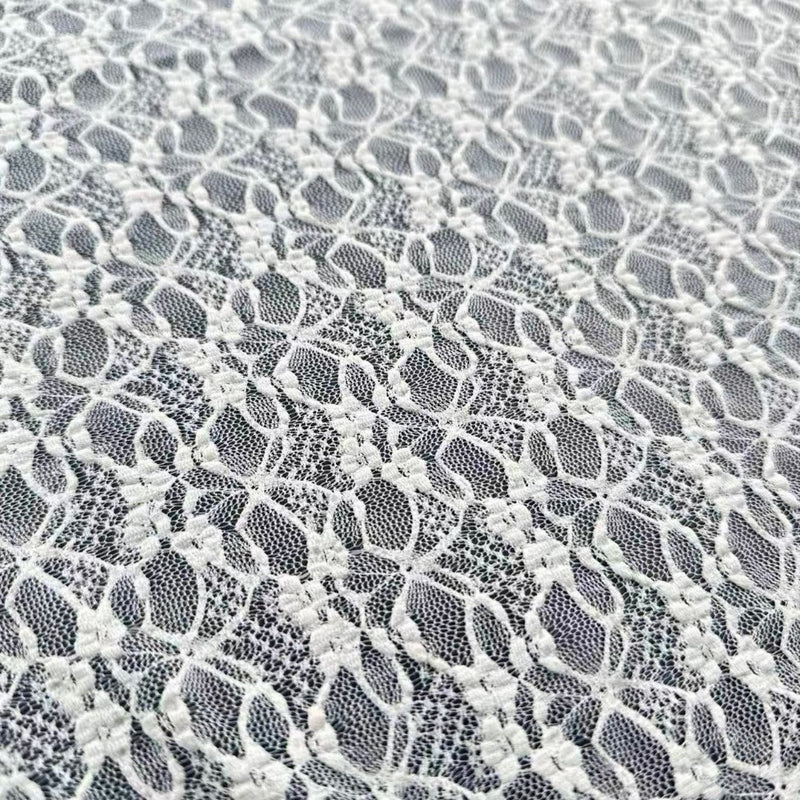Close-up of white floral lace with repeating oval mesh openings and small embroidered flower clusters.