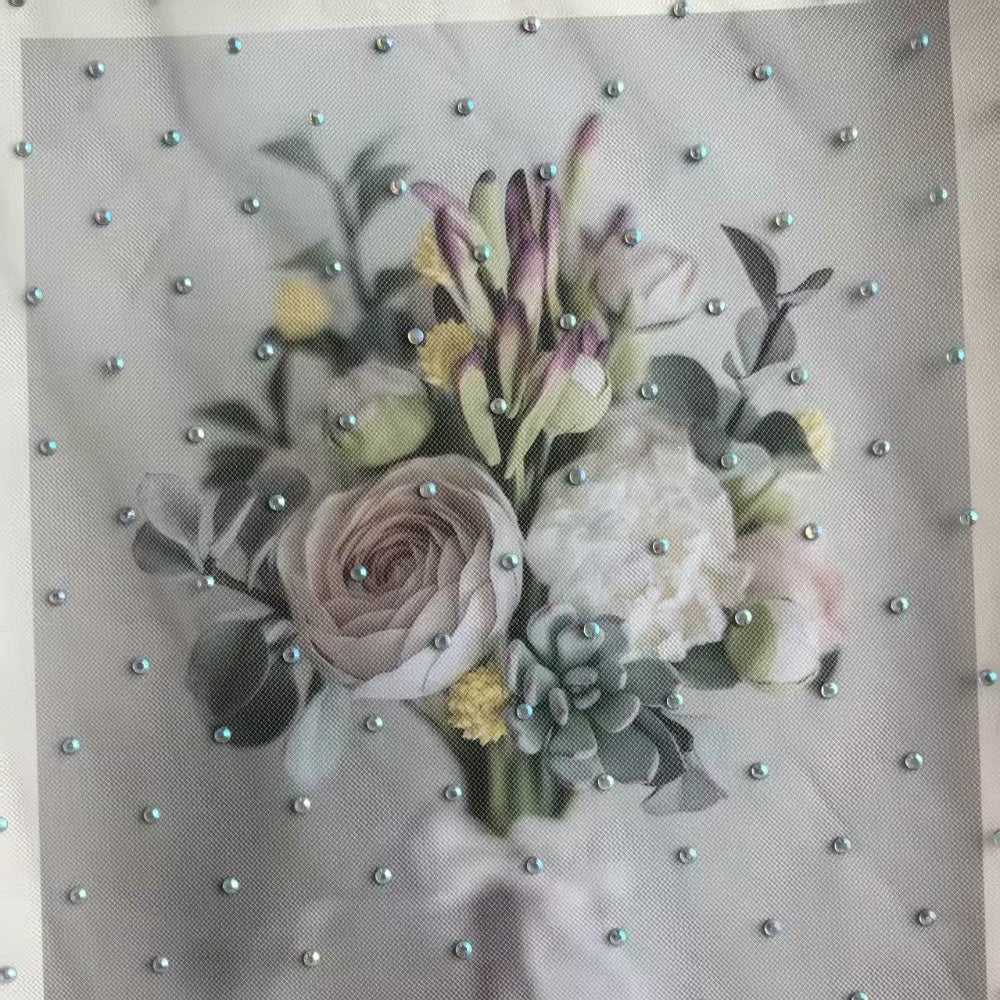 A flat panel of pale gray fabric is decorated with an all-over bouquet of muted pink, white, yellow, and green flowers and leaves, with small blue-silver studs scattered across the surface.