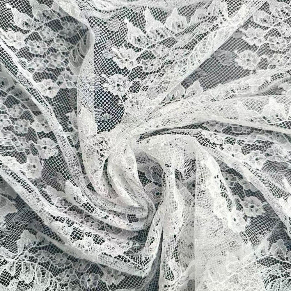 Close-up of white floral lace with an open net pattern, draped in overlapping curved folds.