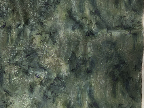Close-up of mottled dark green and gray fabric with scattered black bird-like motifs and fine pale streaks.