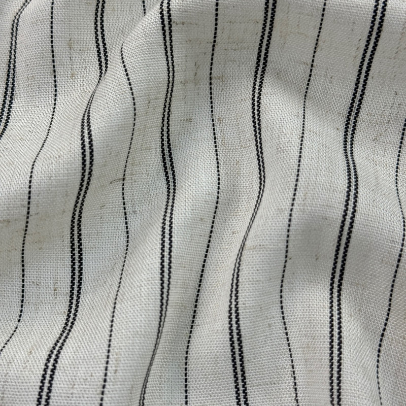 Close-up of light gray woven fabric with irregular vertical black stripes, shown in gentle folds.