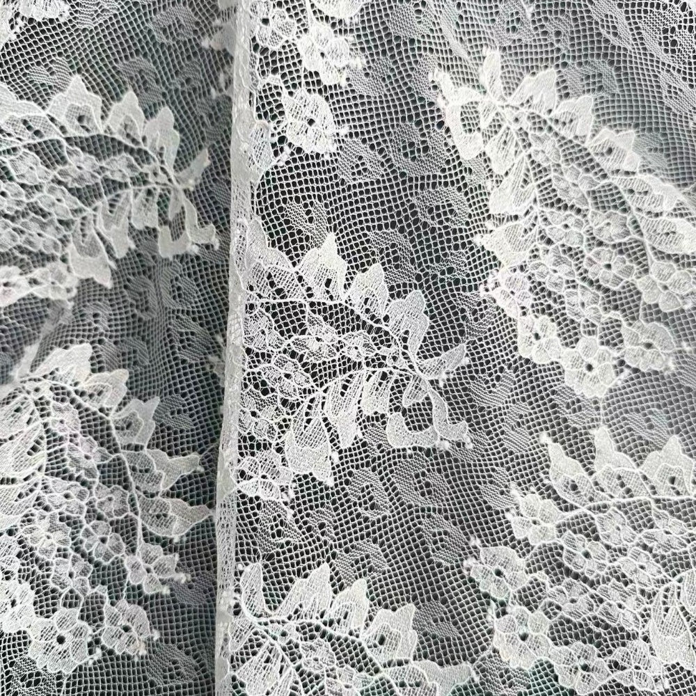 Close-up of pale ivory lace with a fine mesh ground and raised floral motifs, arranged in overlapping panels.