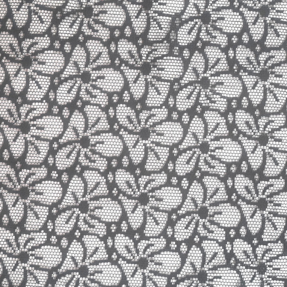 Close-up of black lace with a repeating geometric floral motif arranged in horizontal rows; a light background shows through the mesh.