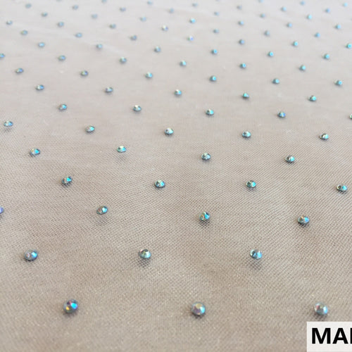 Pale beige mesh fabric is shown flat, covered with evenly spaced small iridescent blue and silver studs.