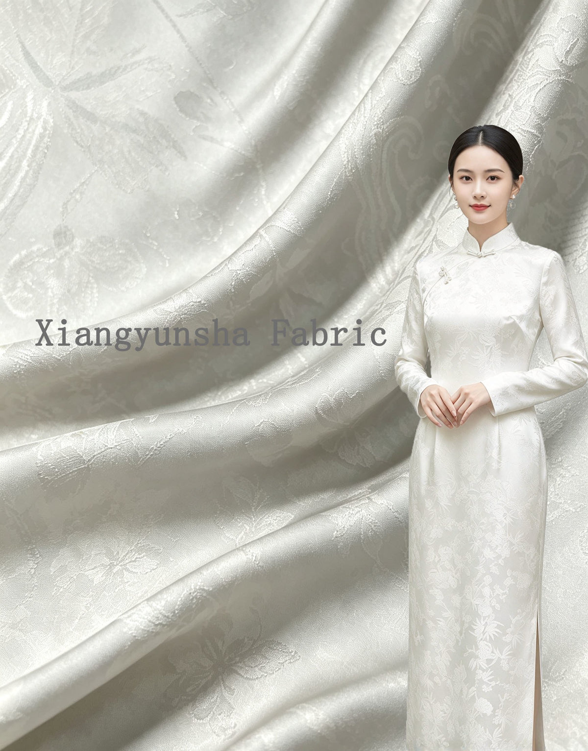 A woman wears a floor-length white garment with a subtle floral motif, posed against a backdrop of draped white and pale gray patterned fabric; full garment view.