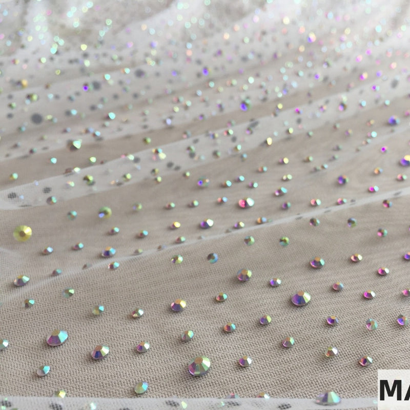 Taupe mesh fabric is shown in flowing diagonal folds, scattered with small iridescent round and faceted embellishments in assorted colors.